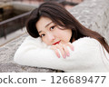 一位身穿白衣的年輕女子在港口休息 126689477
