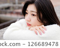 一位身穿白衣的年輕女子在港口休息 126689478