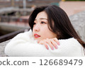 一位身穿白衣的年輕女子在港口休息 126689479