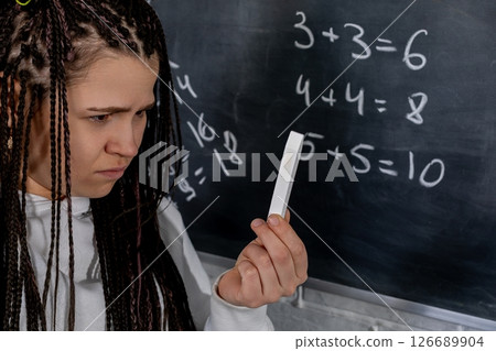A student deeply contemplating various complex math problems written on a chalkboard A student deeply contemplating various complex math problems written on a chalkboard 126689904