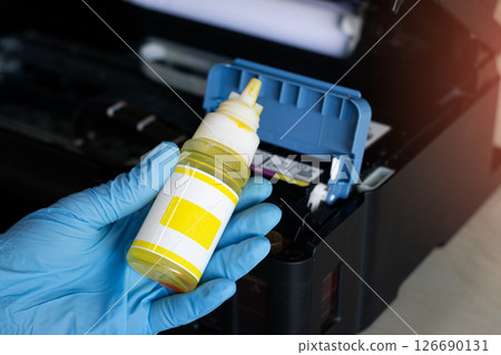 Side view of technician filling printer with ink. Side view of technician filling printer with ink. 126690131