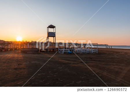 Beautiful sunrise scene on an empty beach featuring a lifeguard tower Beautiful sunrise scene on an empty beach featuring a lifeguard tower 126690372
