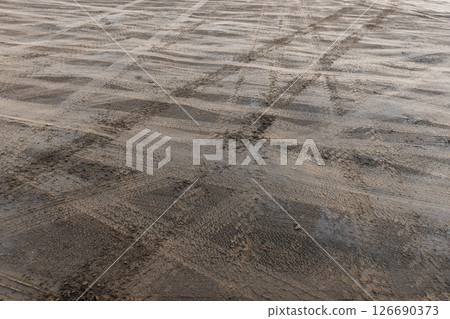 Uneven beach ground surface with visible vehicle tire tracks Uneven beach ground surface with visible vehicle tire tracks 126690373