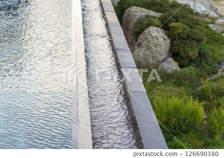 A serene water feature with overflowing water beside rocks 126690380
