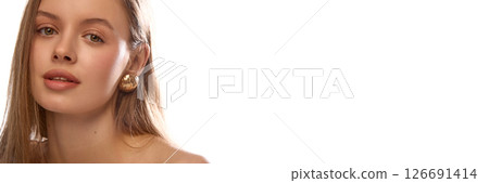 Banner. Woman with golden earring, looking straight at camera with calm expression against with studio background with copy space. 126691414