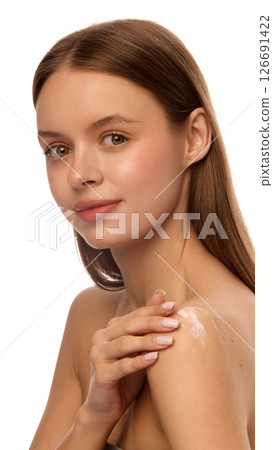 Portrait of woman gently touching shoulder with hand after applying skincare cream, with clean smooth skin, healthy effect against white studio background 126691422