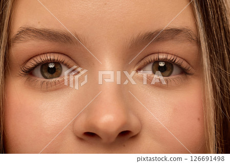 Close-up of young woman's face showing clean skin and bright eyes with natural makeup, long lashes and smooth eyebrows in soft light. Close-up of young woman's face showing clean skin and bright eyes with natural makeup, long lashes and smooth eyebrows in soft light. 126691498