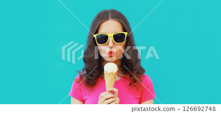 Summer portrait of happy young woman eating ice cream on blue background Summer portrait of happy young woman eating ice cream on blue background 126692748