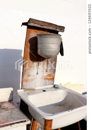 Old rusty metal washbasin with a sink underneath 126693920