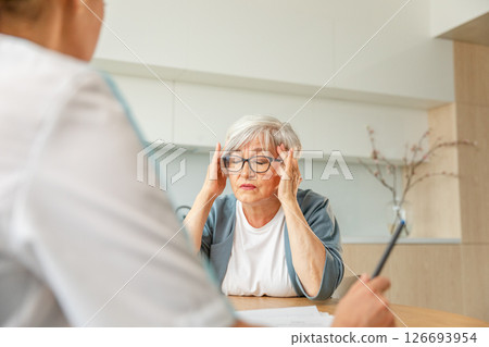 Female doctor examining older senior woman in doctor office or at home. Old woman lady patient and doctor have consultation in hospital room. Medicine healthcare medical checkup. Visit to doctor 126693954