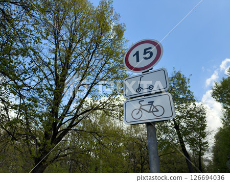 Traffic sign limiting speed for electric scooters and bicycles, symbolizing the integration of micro mobility into modern urban park infrastructure surrounded by spring greenery Traffic sign limiting speed for electric scooters and bicycles, symbolizing the integration of micro mobility into modern urban park infrastructure surrounded by spring greenery 126694036