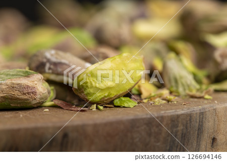 pistachios peeled from the shell, salted crunchy nuts, pistachios without shells, cut into pieces on a board, closeup, side view pistachios peeled from the shell, salted crunchy nuts, pistachios without shells, cut into pieces on a board, closeup, side view 126694146