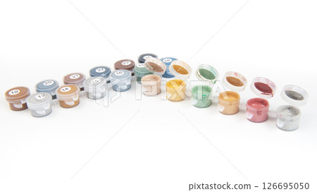 Small jars filled with paint on a painted canvas. Painting by numbers. Bright and colorful. Small jars filled with paint on a painted canvas. Painting by numbers. Bright and colorful. 126695050
