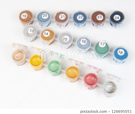 Small jars filled with paint on a painted canvas. Painting by numbers. Bright and colorful. Small jars filled with paint on a painted canvas. Painting by numbers. Bright and colorful. 126695051