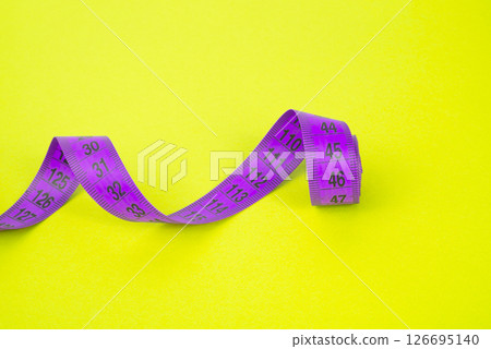 Colored centimeter tape on yellow background with copyspace Colored centimeter tape on yellow background with copyspace 126695140