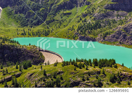 Turquoise Grossglockner glacier reservoir  Speicher Margaritzen alpine slopes and forested hills with concrete dam structure at valley edge. High-altitude lake in vibrant natural mountain scenery 126695691