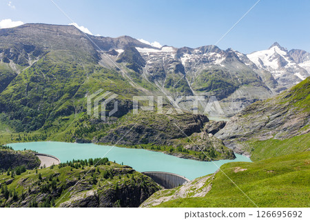 Turquoise Grossglockner glacier reservoir Speicher Margaritzen alpine slopes and forested hills with concrete dam structure at valley edge. High-altitude lake in vibrant natural mountain scenery Turquoise Grossglockner glacier reservoir Speicher Margaritzen alpine slopes and forested hills with concrete dam structure at valley edge. High-altitude lake in vibrant natural mountain scenery 126695692