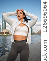 Sporty Woman Stretching Outdoors by the City Waterfront at Sunrise 126696064