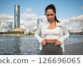 Sporty Woman Stretching Outdoors by the City Waterfront at Sunrise 126696065
