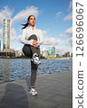 Sporty Woman Stretching Outdoors by the City Waterfront at Sunrise 126696067