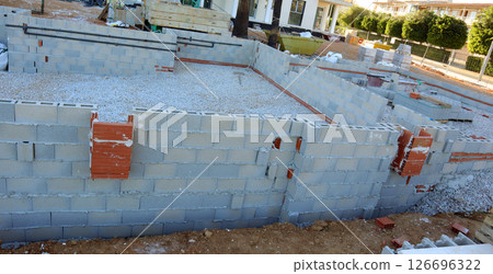 Workers begin the construction of a pool in the courtyard of a charming cottage, laying the foundation with blocks and gravel, preparing for the next steps in the building process. 126696322