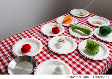 Colorful plush vegetables on checkered tablecloth with white plates 126696337