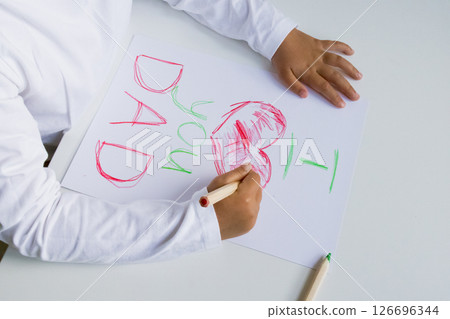 Child drawing heartfelt message with crayons for dad on white paper surface. Father day 126696344