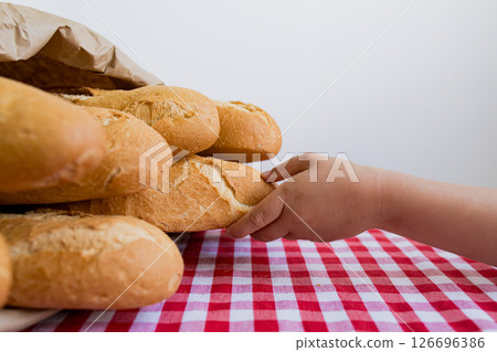 Child reaching for fresh baked bread on checkered tablecloth 126696386