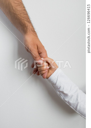 Adult caucasian male hand gently holding child hand against white background 126696415
