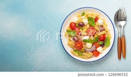 Italian pasta salad with fusilli, cherry tomatoes, mozzarella, olives, basil on blue background top view, Italian cuisine, space for text 126696532