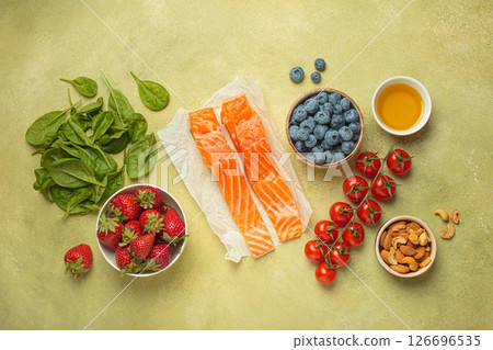 Healthy food for anti inflammatory diet: fish, vegetables, berries, nuts, olive oil, spinach top view on green background 126696535