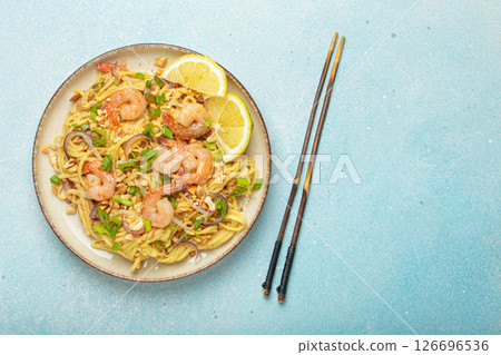 Pad thai noodles with shrimps and chopsticks on light blue background, traditional dish of Thailand, copy space 126696536