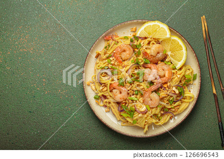Pad thai noodles with shrimps and chopsticks on rustic green background, traditional dish of Thailand, space for text 126696543