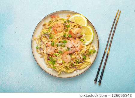 Pad thai noodles with shrimps and chopsticks on light blue background, traditional dish of Thailand Pad thai noodles with shrimps and chopsticks on light blue background, traditional dish of Thailand 126696548
