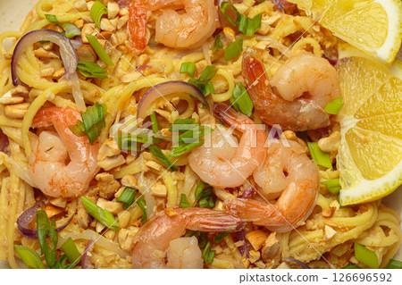 Pad thai noodles with shrimps, peanuts, green onions and lemon slice close up 126696592