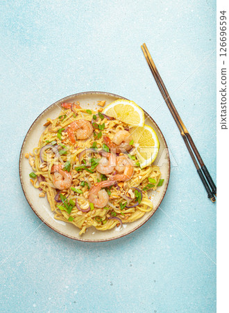Pad thai noodles with shrimps and chopsticks on light blue background, traditional dish of Thailand Pad thai noodles with shrimps and chopsticks on light blue background, traditional dish of Thailand 126696594