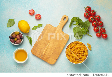 Italian or Mediterranean cuisine food ingredients arranged around empty cutting board on blue background top view Italian or Mediterranean cuisine food ingredients arranged around empty cutting board on blue background top view 126696610