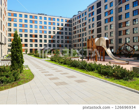A Modern Apartment Complex featuring a Playground situated in a Beautiful Green Setting 126696934