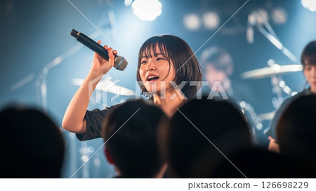 一位女士在舞台上用麥克風唱歌 126698229