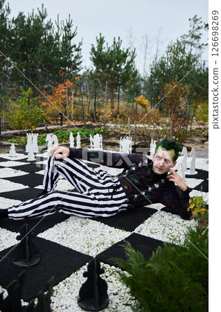 A Fashionable Chessboard Pose in Stylish Striped Attire Set Against a Beautiful Background 126698269