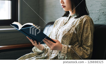 一個女人坐在沙發上和閱讀 一個女人坐在沙發上和閱讀 126698325