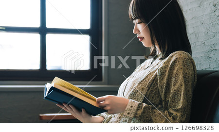 A woman sitting on a sofa and reading 126698328