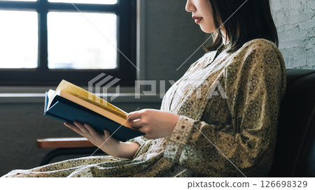 一個女人坐在沙發上和閱讀 126698329