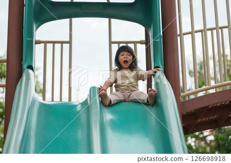 happy toddler baby girl sliding and playing at playground happy toddler baby girl sliding and playing at playground 126698918