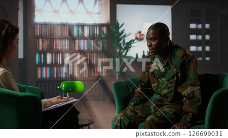 Military war veteran is in a vulnerable state opening up about combat horror scenes, crying and feeling frustrated after losing troopers. Serviceman discussing about traumatic experiences. Camera A. 126699031