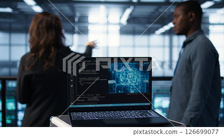 Focus on laptop used by teamworking data center computer scientists in background using artificial intelligence. Notebook screen with neural networks doing computing processes, camera B close up Focus on laptop used by teamworking data center computer scientists in background using artificial intelligence. Notebook screen with neural networks doing computing processes, camera B close up 126699077