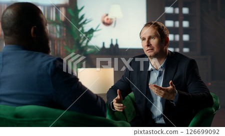 Two diverse gentlemen in a private classy social club discussing career advancement and money making while they are enjoying a sophisticated whiskey experience. Upper class society. Camera B. 126699092