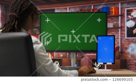 Freelancer in home office using green screen PC and mockup tablet to work on job tasks. Teleworker using chroma key computer monitor and isolated screen device to do job online 126699103