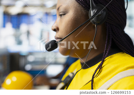 Solar power female engineer giving remote support on headset call in factory, working in customer service call center. Operator sales representative gives assistance, industrial facility. Solar power female engineer giving remote support on headset call in factory, working in customer service call center. Operator sales representative gives assistance, industrial facility. 126699153