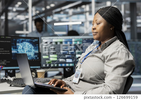 Data center admin using artificial intelligence neural networks node trees on laptop. Server room specialist using using AI programming language on notebook, configuring specialized hardware 126699159